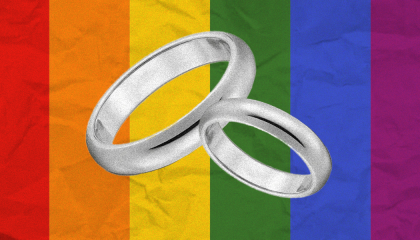 A pair of silver rings in front of a pride flag background