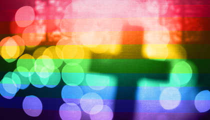 A silhouette of a cross with a rainbow overlaid and glimmer effects